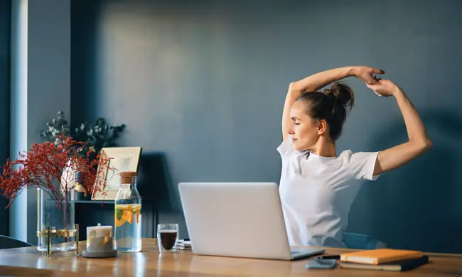 a woman stretching at her desk