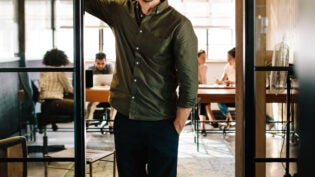 A man smiling and standing in an open doorway to an office