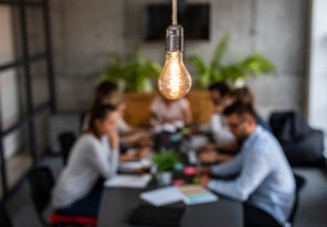 a lightbulb above a meeting emphasizing bright ideas in business