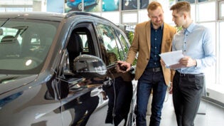 a car salesperson showing a customer a vehicle