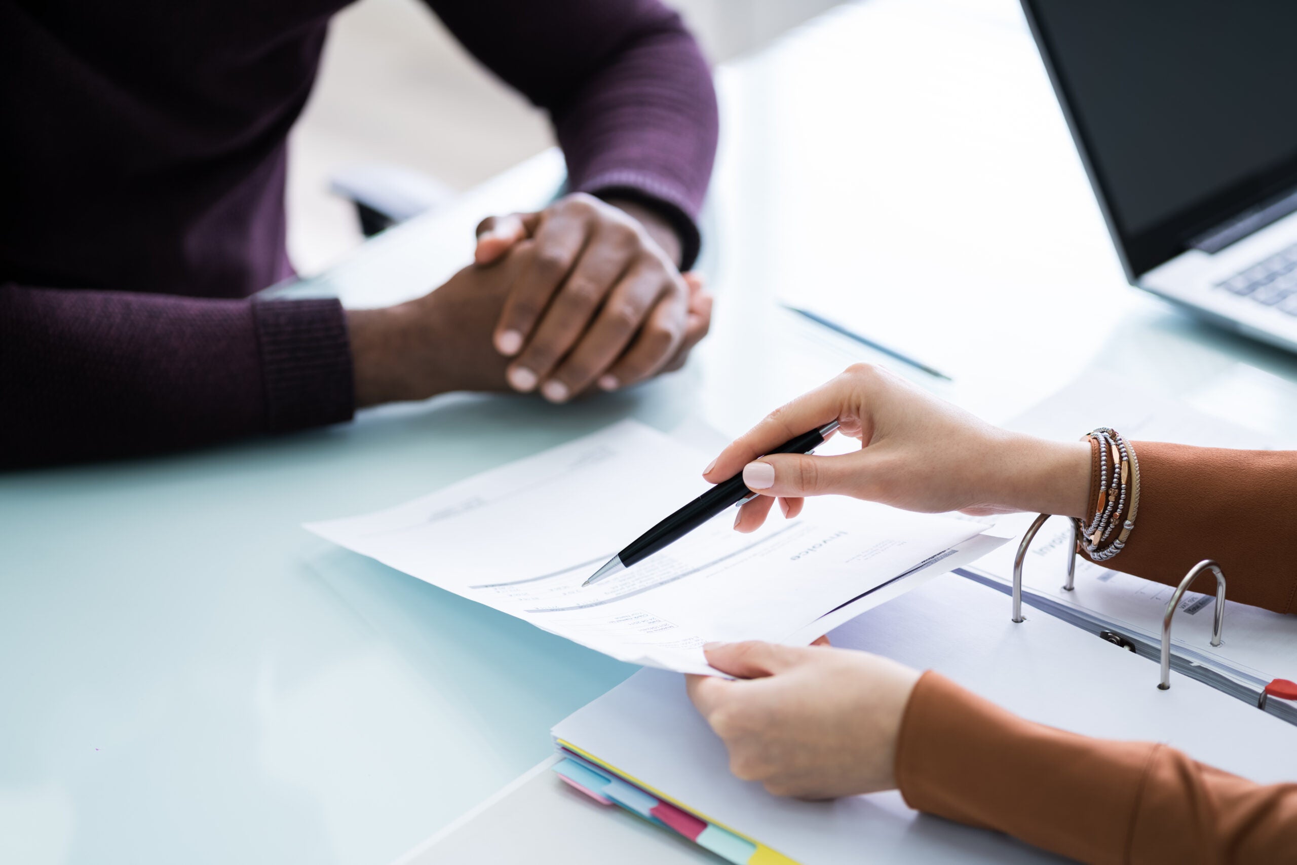 Young Financial Advisor Discussing Invoice With Her Client At Workplace