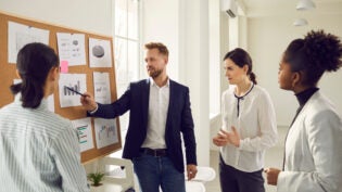 a team member pointing to a graph as other team members look on