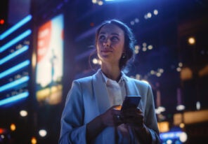 a woman smiling as she uses her android device