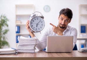 a person pointing at a clock implying time isn't being used effectively