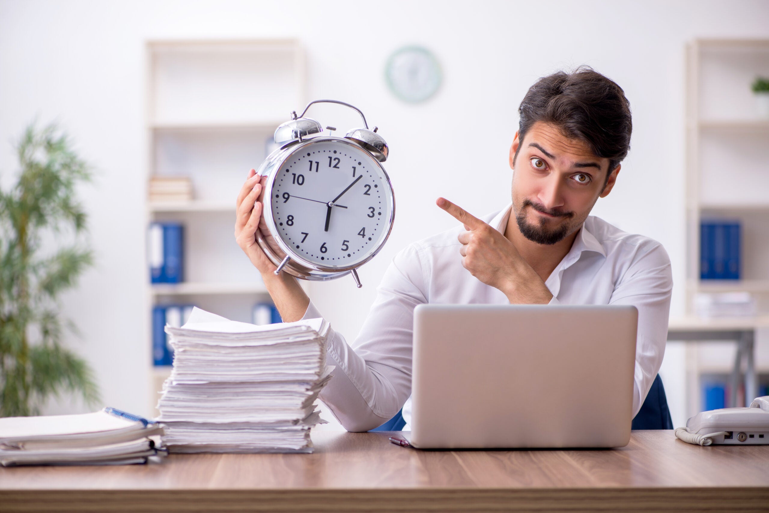 a person pointing at a clock implying time isn't being used effectively