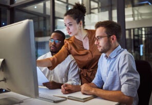 A team member showing two other team members information on a computer