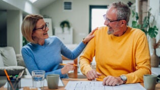 Happy senior couple enjoying their time at home and examining housing plans while relocating into a new house. Elderly couple moving into a new house. Investing in the new property, mortgage.