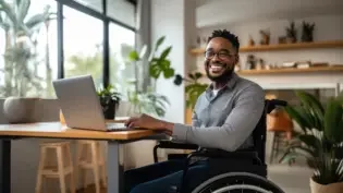 a man in a wheelchair working happily at his job