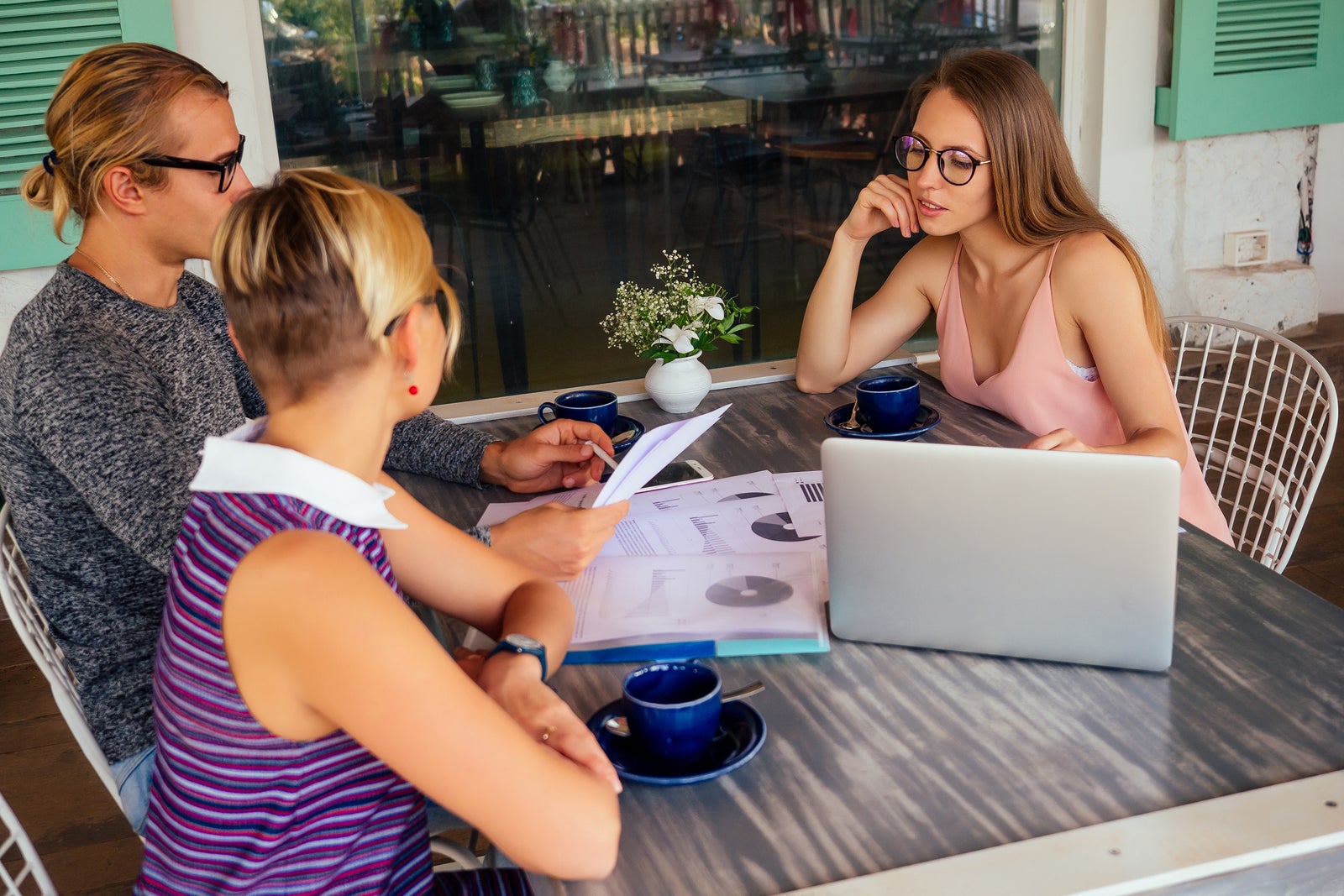 Business team meeting. Successful business partners working together with laptop, while sitting in urban summer cafe outdoors.freelancer distant remote work teamwork