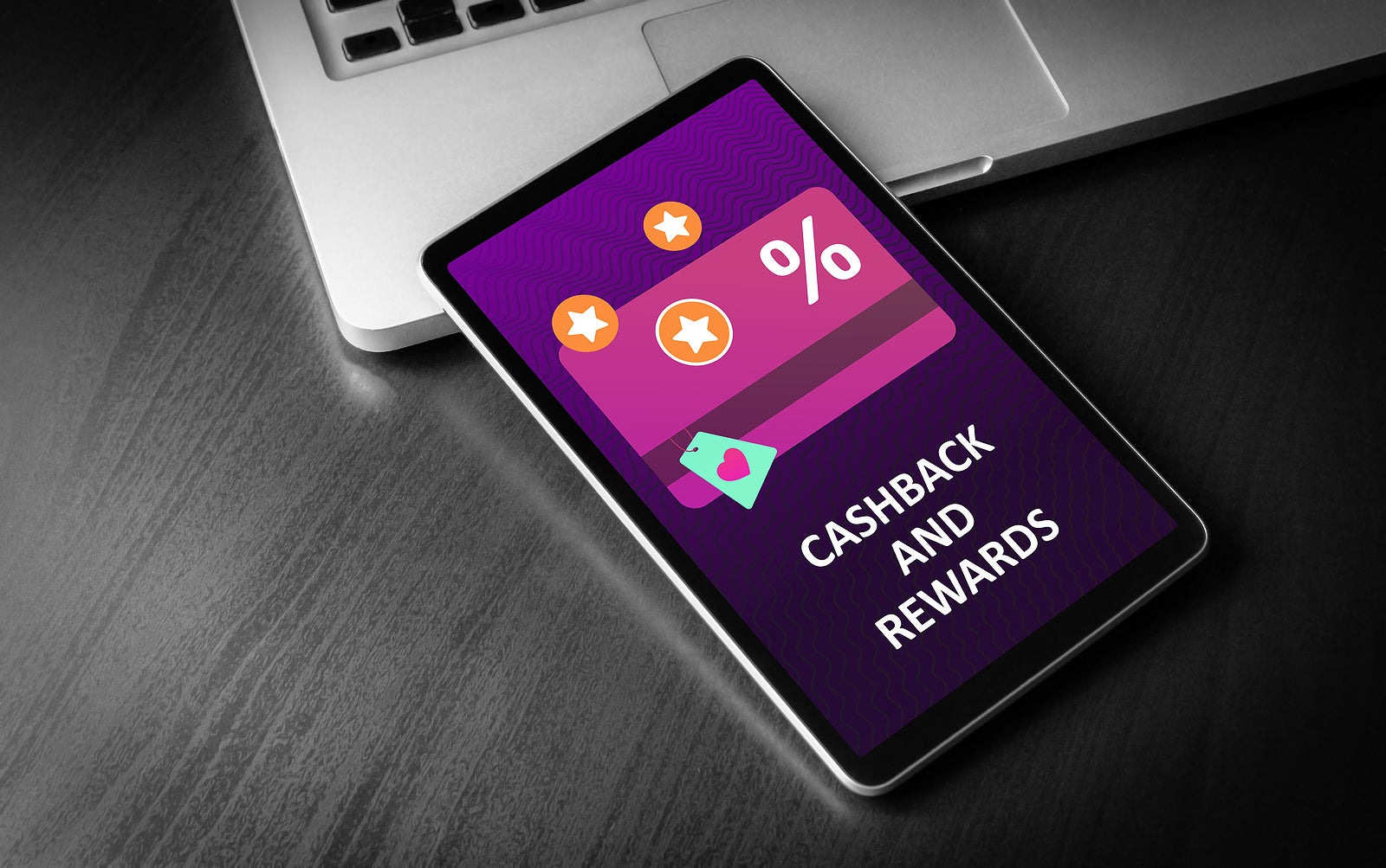 Cashback and Rewards - loyalty program and retail customer money refund service concept. Tablet PC lying on a wooden table with discount card with rewarding marketing points on the screen