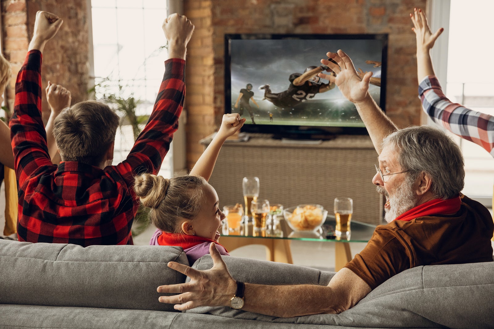 Victory. Excited, happy family watching american football match, championship on the couch at home. Fans emotional cheering for favourite national team. Daughter, dad and grandpa. Sport, TV, having fun.