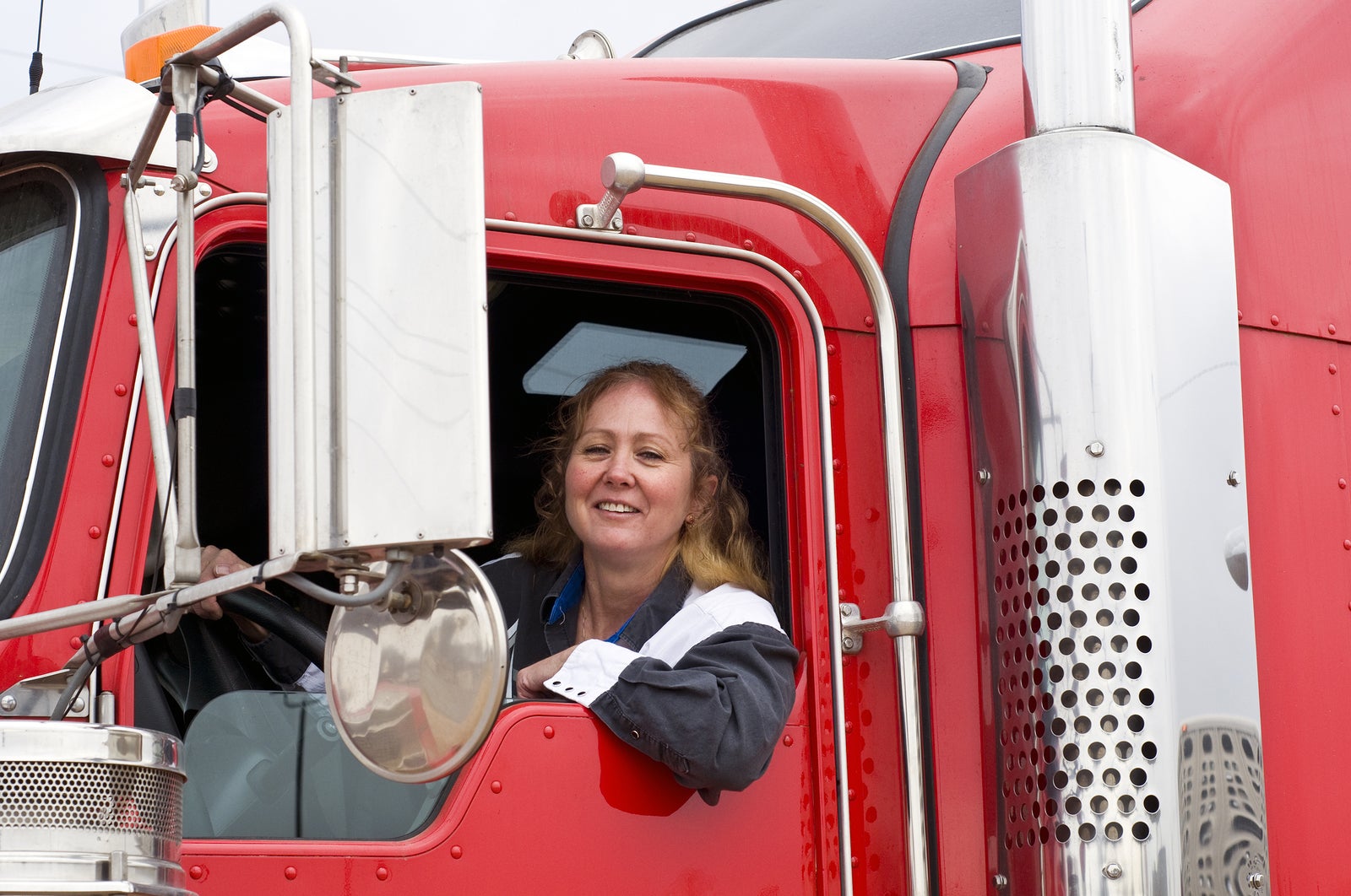 Woman truck driver leaning out the drivers side window.