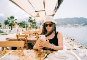 a young entrepreneur checking on her e commerce sales while dining outdoors