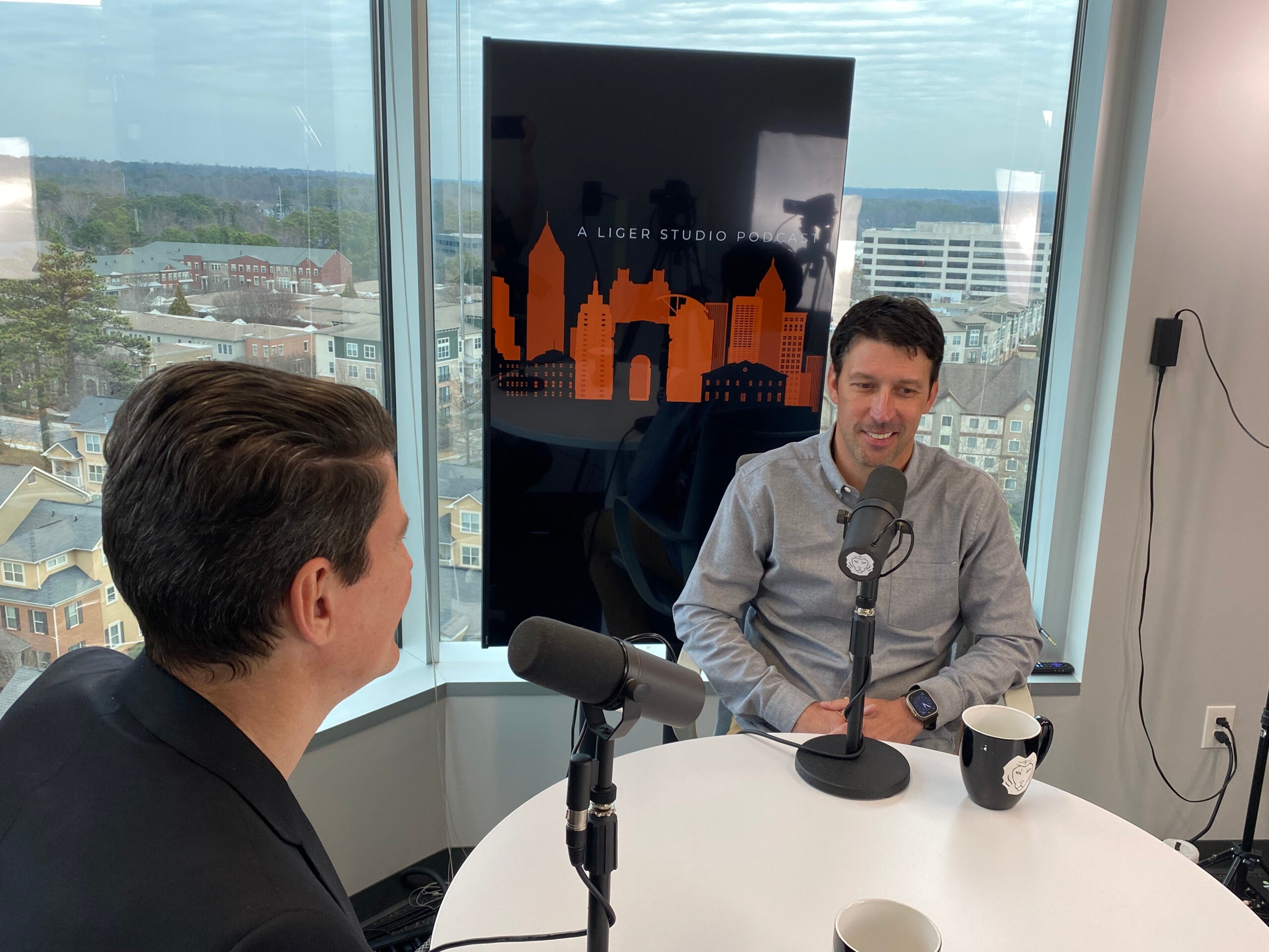 Man in gray shirt speaking with podcast host at table