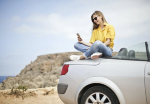 a woman enjoying the sun while sitting on her car