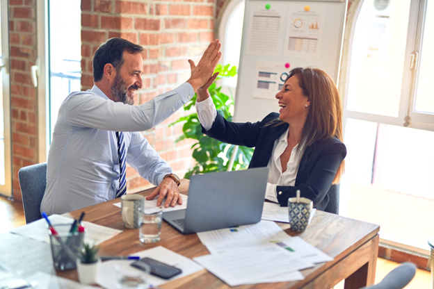 Man and woman high-fiving at work