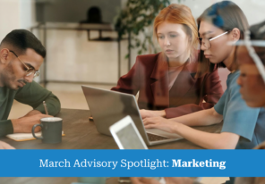 Four professionals are intently looking at a laptop on a desk, collaborating in a business setting